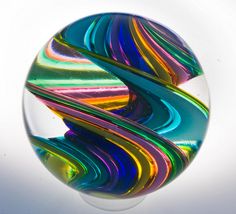 a glass ball with multicolored swirls in the center on a white background