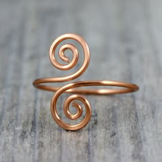 a gold ring with two spirals on it sitting on top of a wooden table