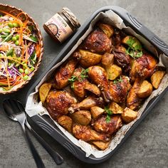 a pan filled with chicken next to a bowl of salad