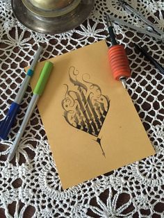 two pens are sitting on top of a piece of paper next to some crocheted doily