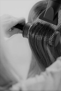 a woman is blow drying her long hair