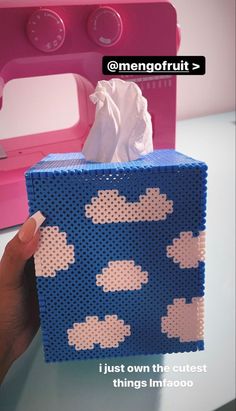 someone is holding up a tissue box made out of perforated material with clouds on it