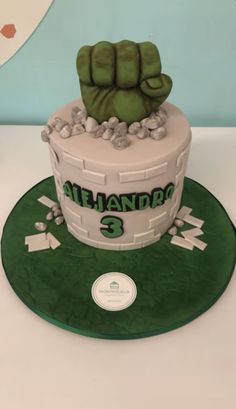 a cake made to look like a fist with the number 3 on it and green frosting