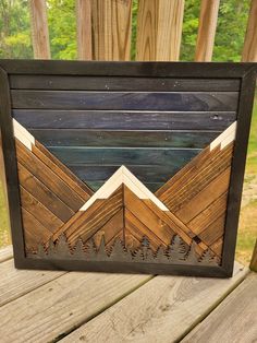 a wooden frame that has some mountains in the middle and trees at the bottom on it