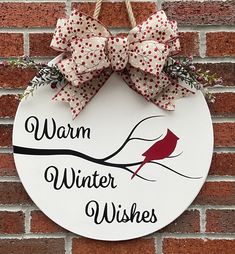 a sign that says warm winter wishes hanging on a brick wall next to a red and white bow