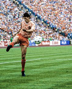 a man kicking a soccer ball on top of a field in front of a crowd