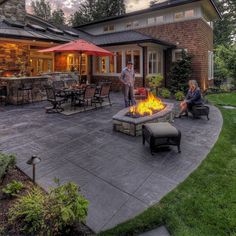 two people sitting around a fire pit on a patio with an outside dining area in the background