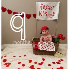 a baby is sitting in a basket with red hearts on it and a free kiss sign