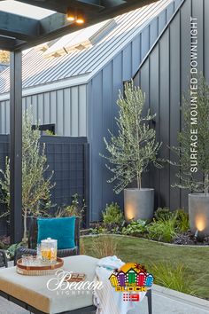 an outdoor living area with couches, tables and potted trees in the background