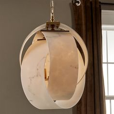 a light fixture hanging from the ceiling in a room with curtains and window behind it