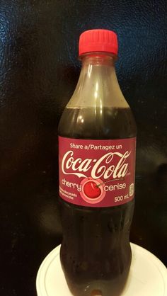 a bottle of coca - cola sitting on top of a white plate with a red cap