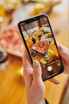 a woman holding up her phone to take a photo of some food on the table