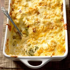 a casserole dish with broccoli and cheese in it on a wooden table