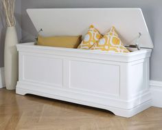 a white storage bench with yellow and white pillows