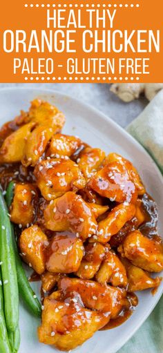 orange chicken with sauce and green beans on a white plate