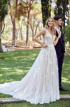 a woman in a wedding dress standing next to a man wearing a tuxedo