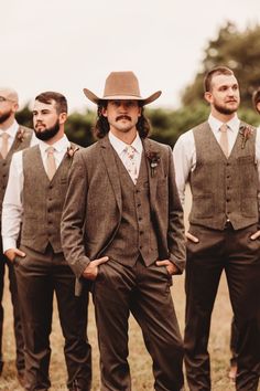 a group of men standing next to each other wearing vests and ties with hats on