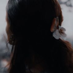 the back of a woman's head with flowers in her hair and an earring