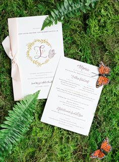 the wedding stationery is laid out on the grass with butterflies around it and tied together