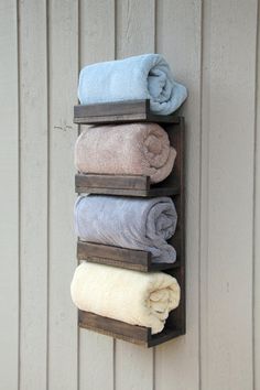 four towels are hanging on a wooden rack