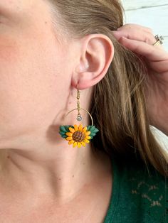 a close up of a person wearing earrings with a sunflower on the front and side