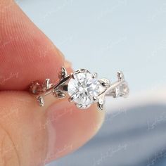 a close up of a person's hand holding a ring with a diamond in it