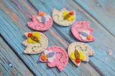 several felt flowers are sitting on a blue wooden surface with water droplets around them and one flower is yellow, the other is pink