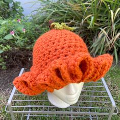 an orange crocheted hat sitting on top of a white mannequin head