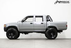 a silver pick up truck parked on top of a tile floor next to a white wall