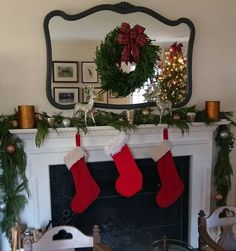 christmas stockings hanging from a mantle in front of a mirror with wreaths on it