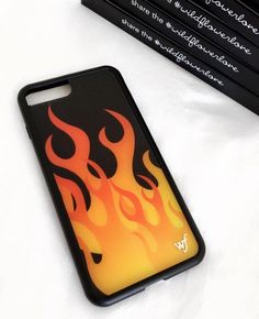 a cell phone case with flames on it next to some books and pencils in the background