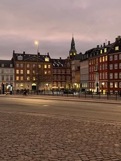 an empty city street at dusk with buildings in the background