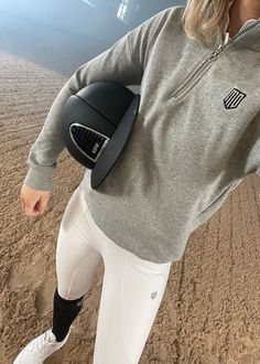 a woman in white pants and a gray sweatshirt with a black helmet on her back