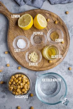 ingredients to make chickpeas laid out on a wooden cutting board with lemons, pepper, garlic and salt