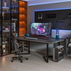 a computer desk with a monitor, keyboard and speakers on it in front of a bookcase