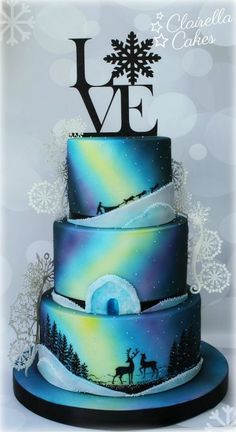 a three tiered cake decorated with an aurora bore and reindeer on the bottom layer