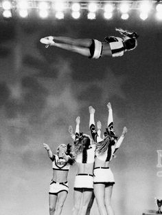 three girls in bathing suits are jumping into the air with their hands up and arms outstretched