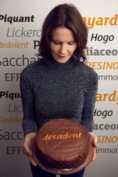 a woman holding a chocolate cake with the word decadent written on it