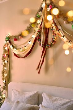 a christmas tree hanging on the wall next to a bed with white sheets and pillows