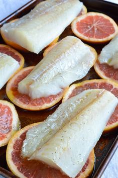 fish fillets are on top of grapefruit slices in a baking pan, ready to be cooked