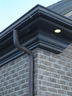 the corner of a brick building with a metal pipe running down it's side