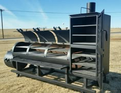 a large black grill sitting on top of a dry grass field