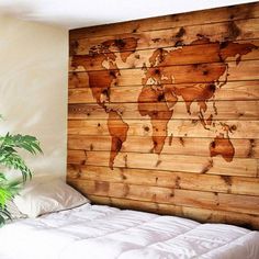 a bed with a wooden world map on the wall above it and a potted plant