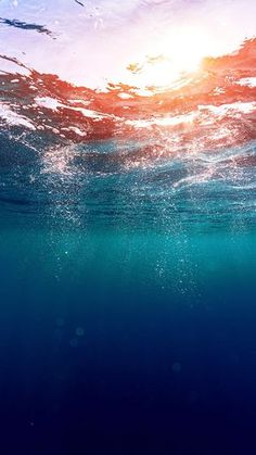 the sun shines brightly through the water as seen from under the ocean surface in this photo