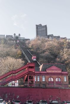 a red building with stairs leading up to the top and cars parked on the street below