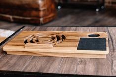 a wooden cutting board with black and white designs on it, sitting on a table