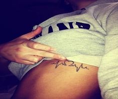 a woman with a heartbeat tattoo on her stomach is pointing at the word'mama '