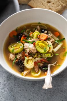 a white bowl filled with soup next to bread on top of a gray countertop