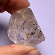 a person holding a piece of crystal in their left hand and the other hand is pointing at it