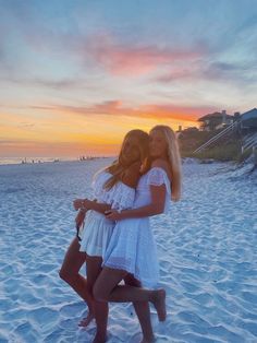 two girls hugging on the beach at sunset